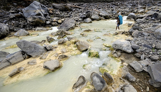 Seorang porter menyeberangi sungai belerang di jalur Torean Gunung Rinjani, Lombok. Di jalur ini terdapat air panas, yang dipercaya penduduk dapat menyembuhkan berbagai penyakit